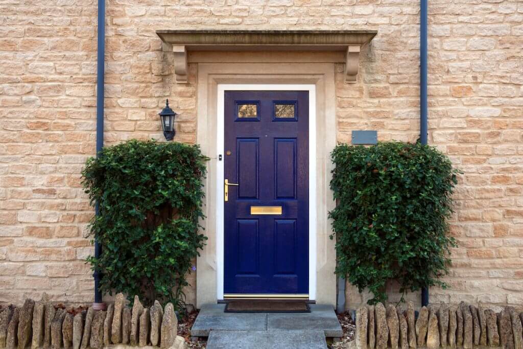 Modern blue painted front door flanked by shrubs